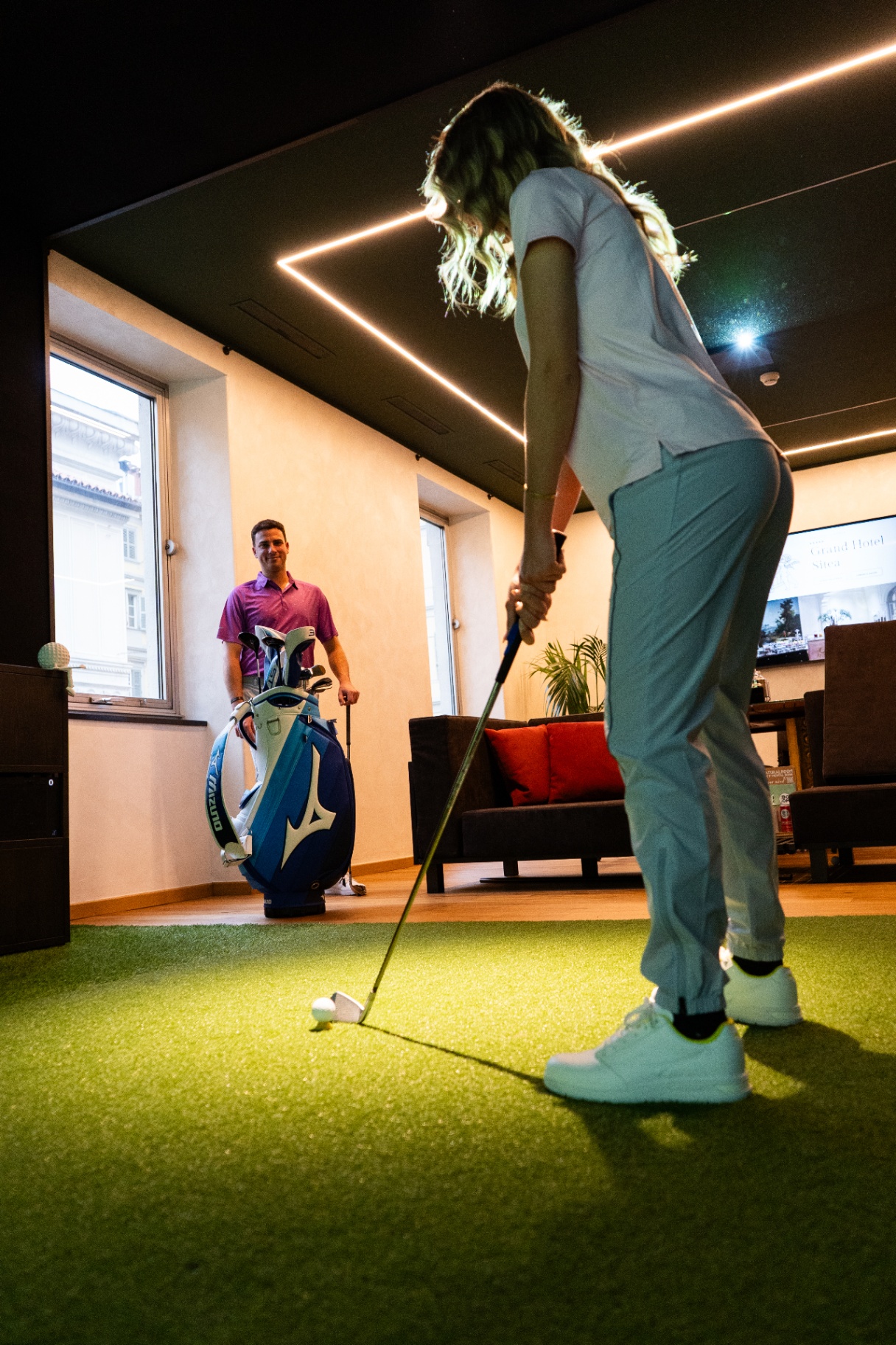 Allieva in fase di putting sul green indoor del golf lounge